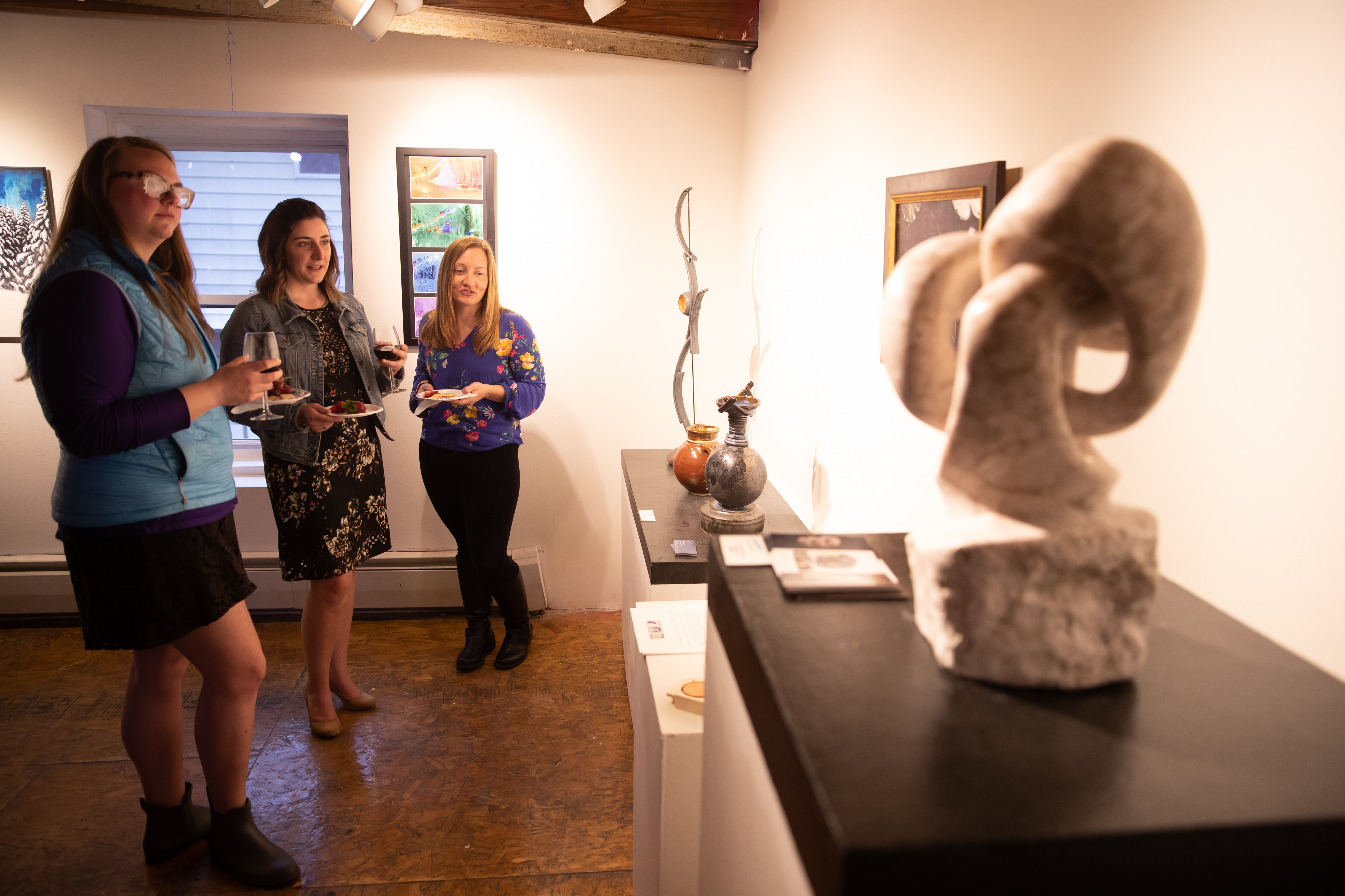 Three women enjoy looking at art