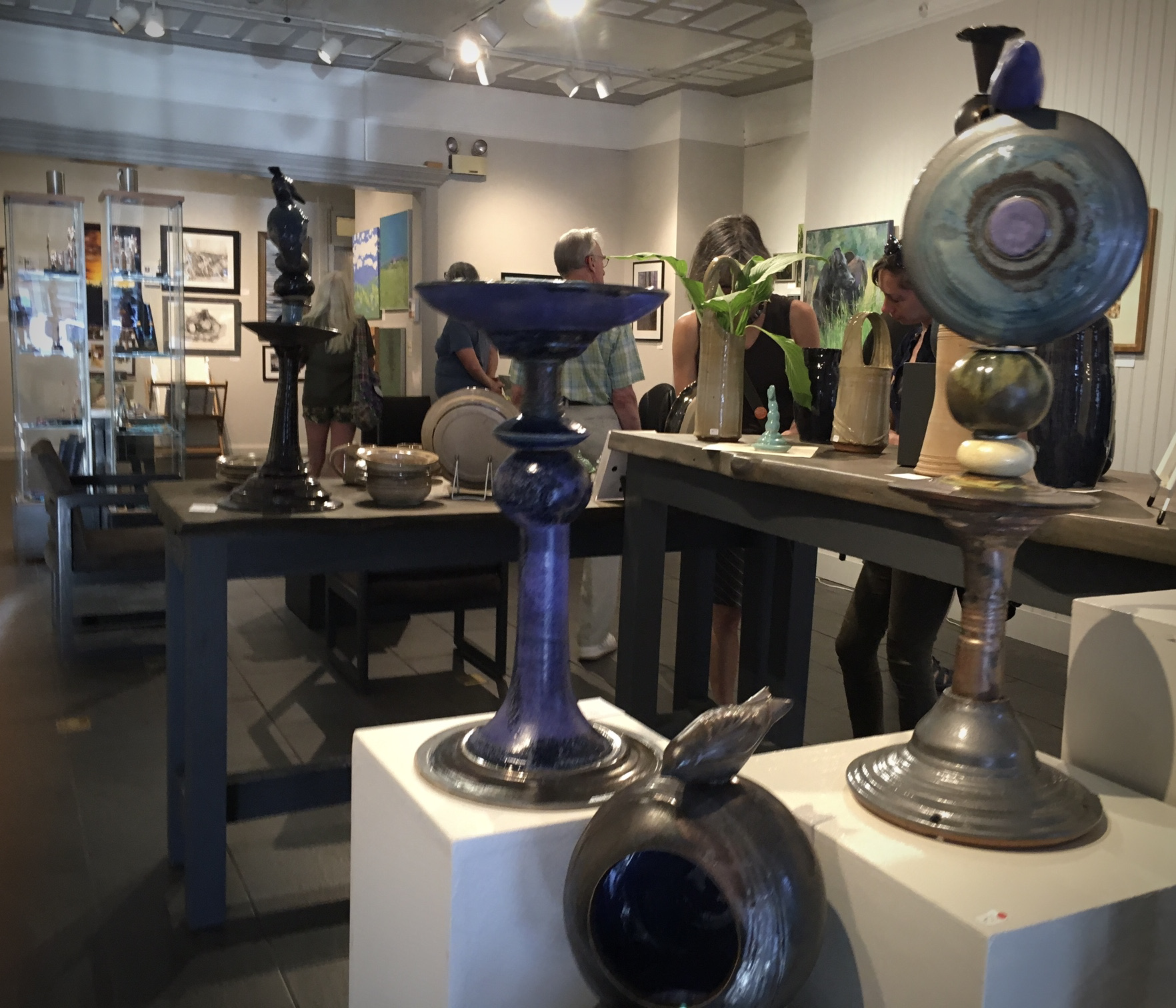 People look at a gallery/studio filled with paintings and ceramics