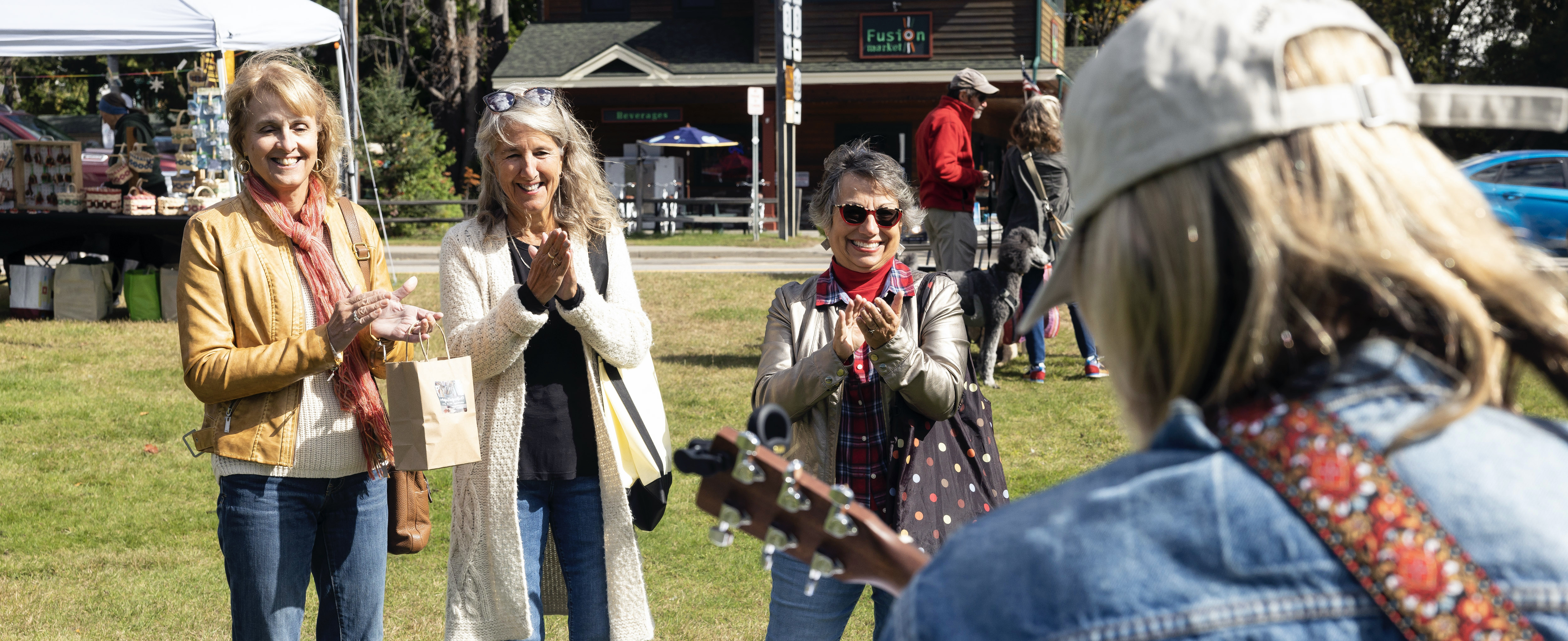 A group of woman clap for someone playing the guitar