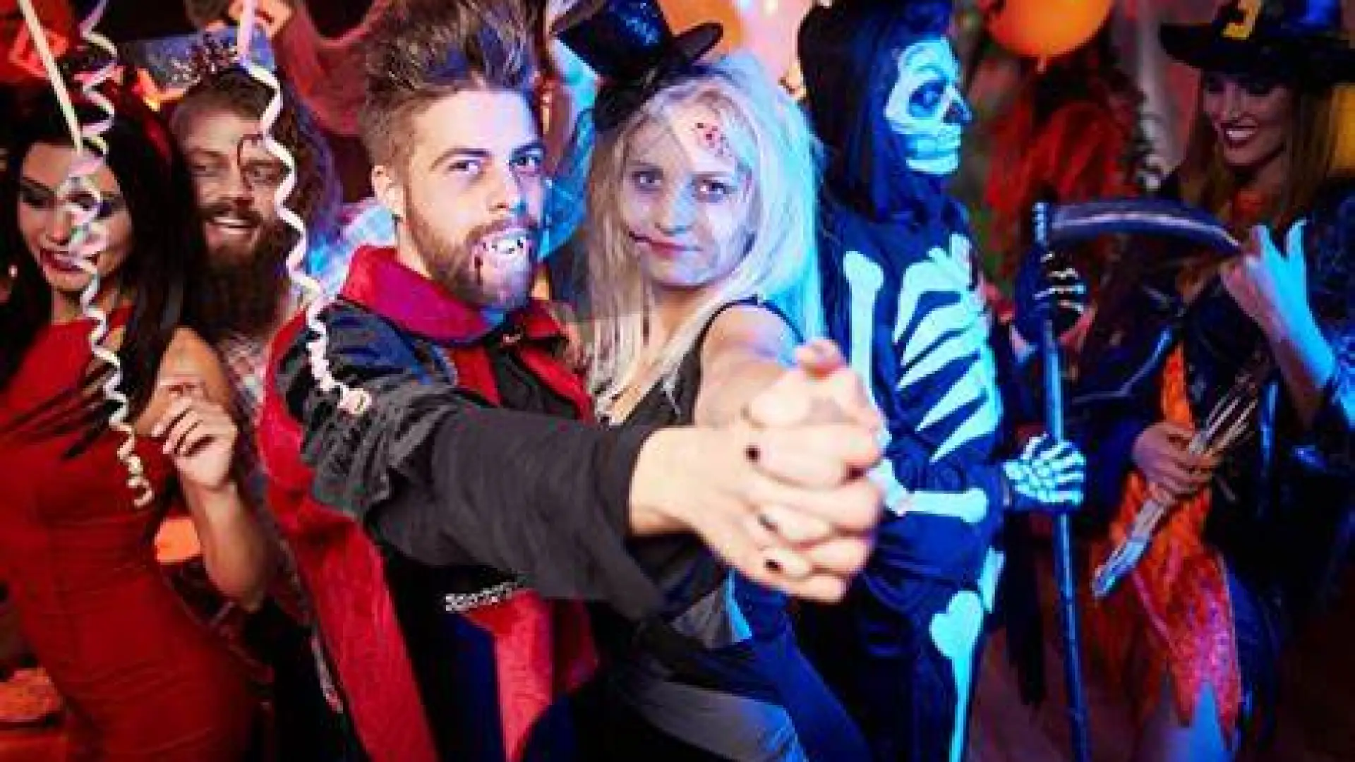 A photo of a man dressed as Dracula and a woman also dressed for halloween dancing at a party
