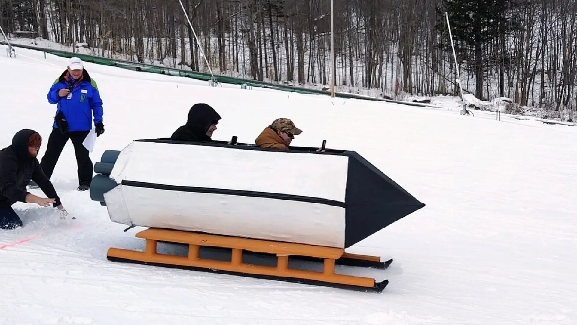 two people going down the hill in a rocketship sled