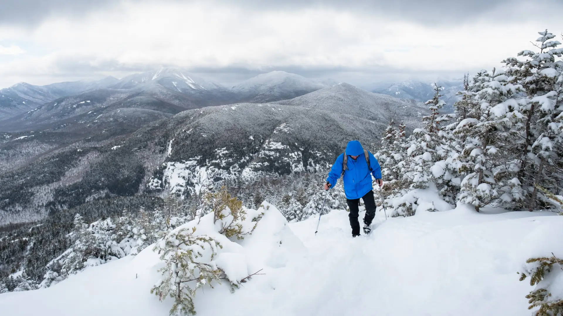A man walks up a snowy mountain trail