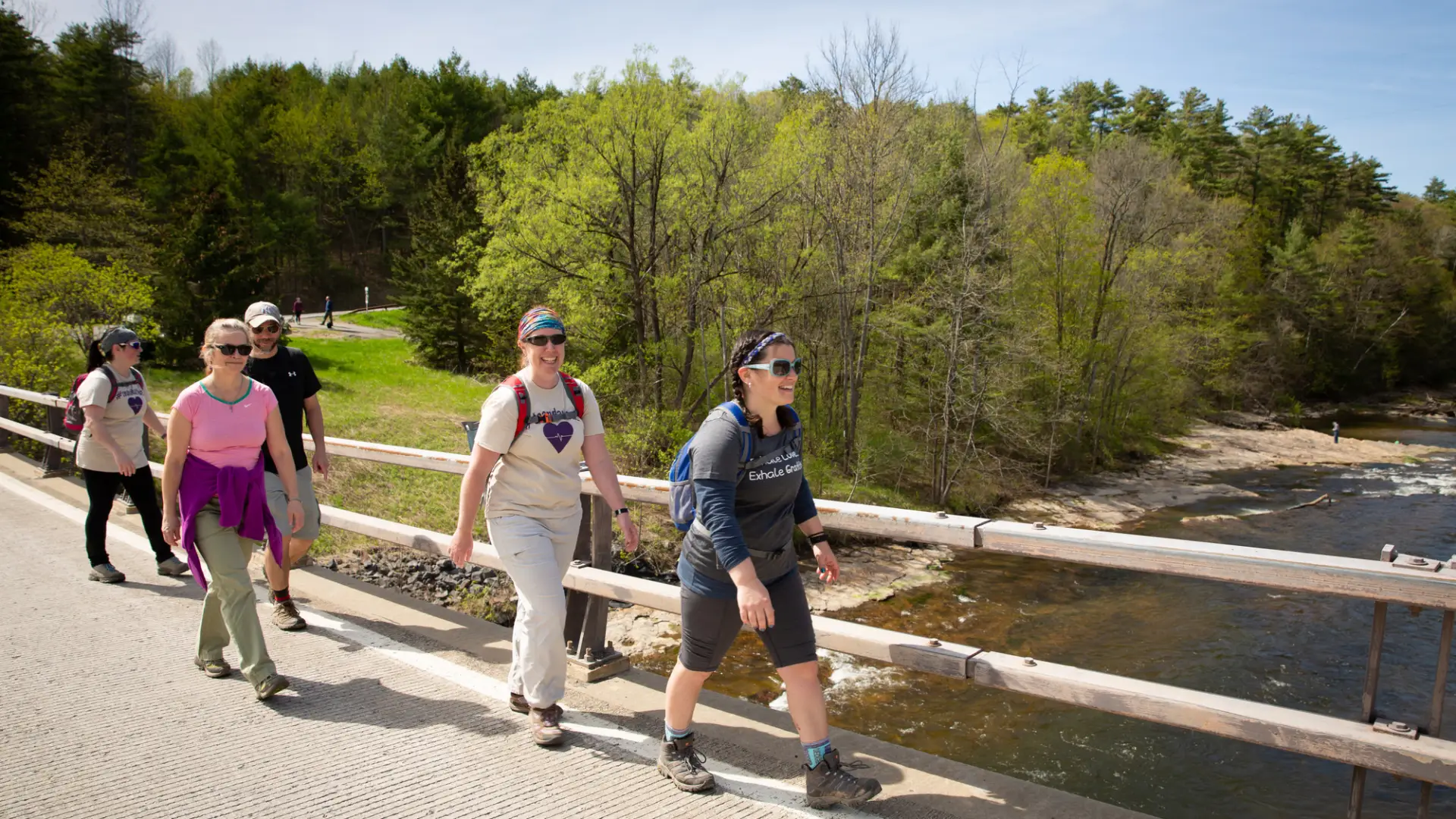 A group of people walking together across a footbridge bridge