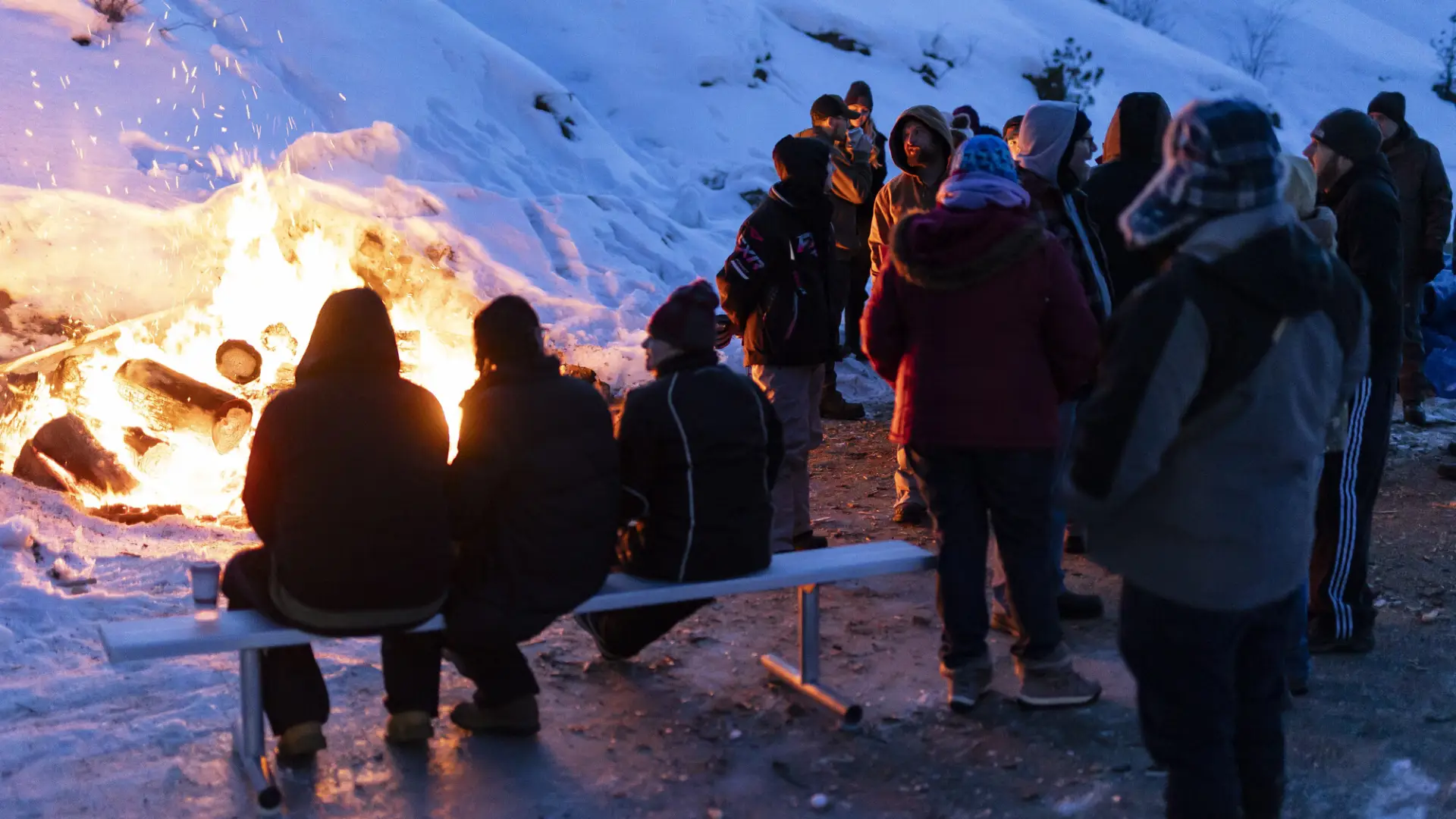 a group of people around a bon fire out in the snow