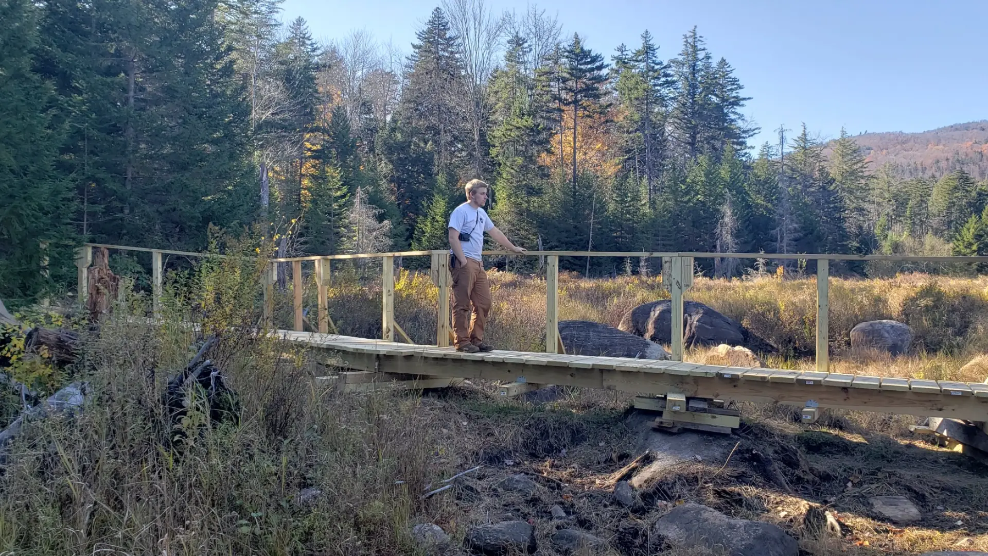 A hiker standing on a wooden bridge