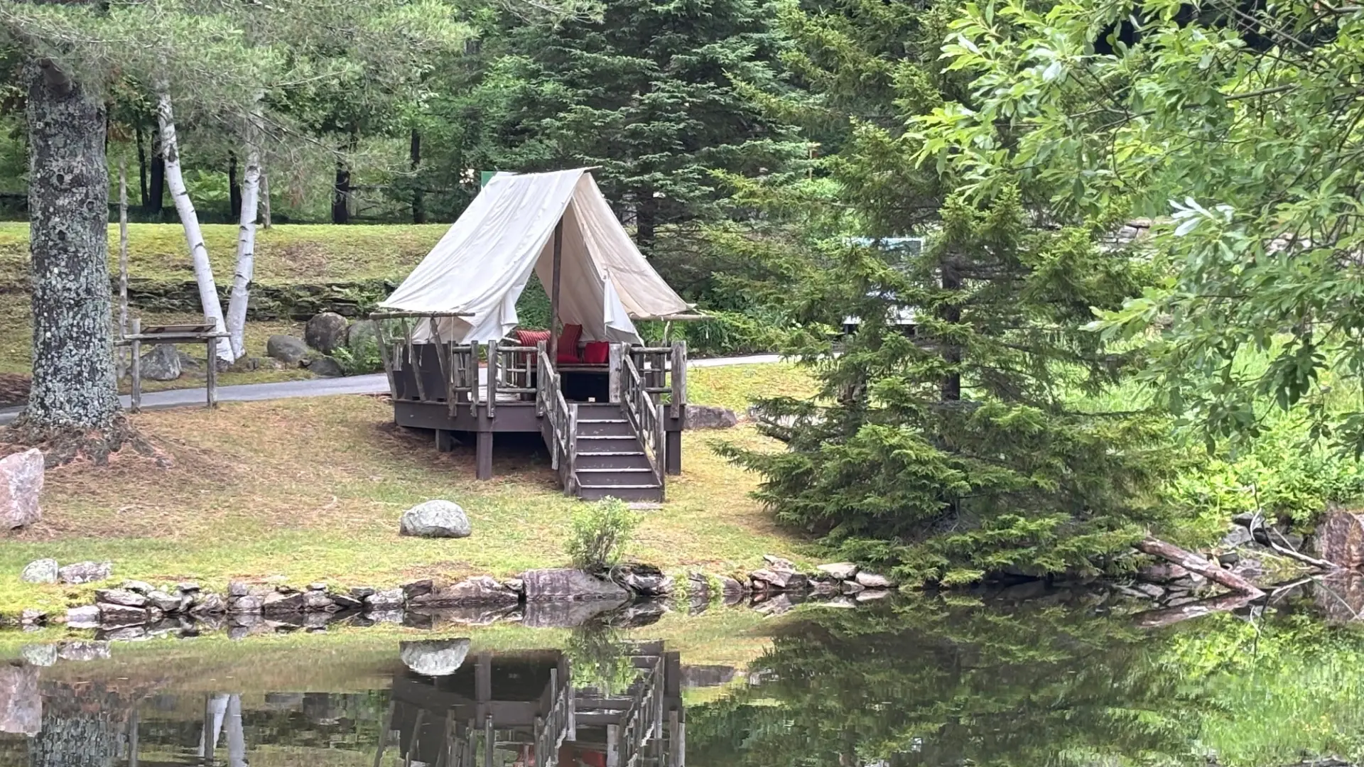 A fabric tent covering a raised deck next to the pond