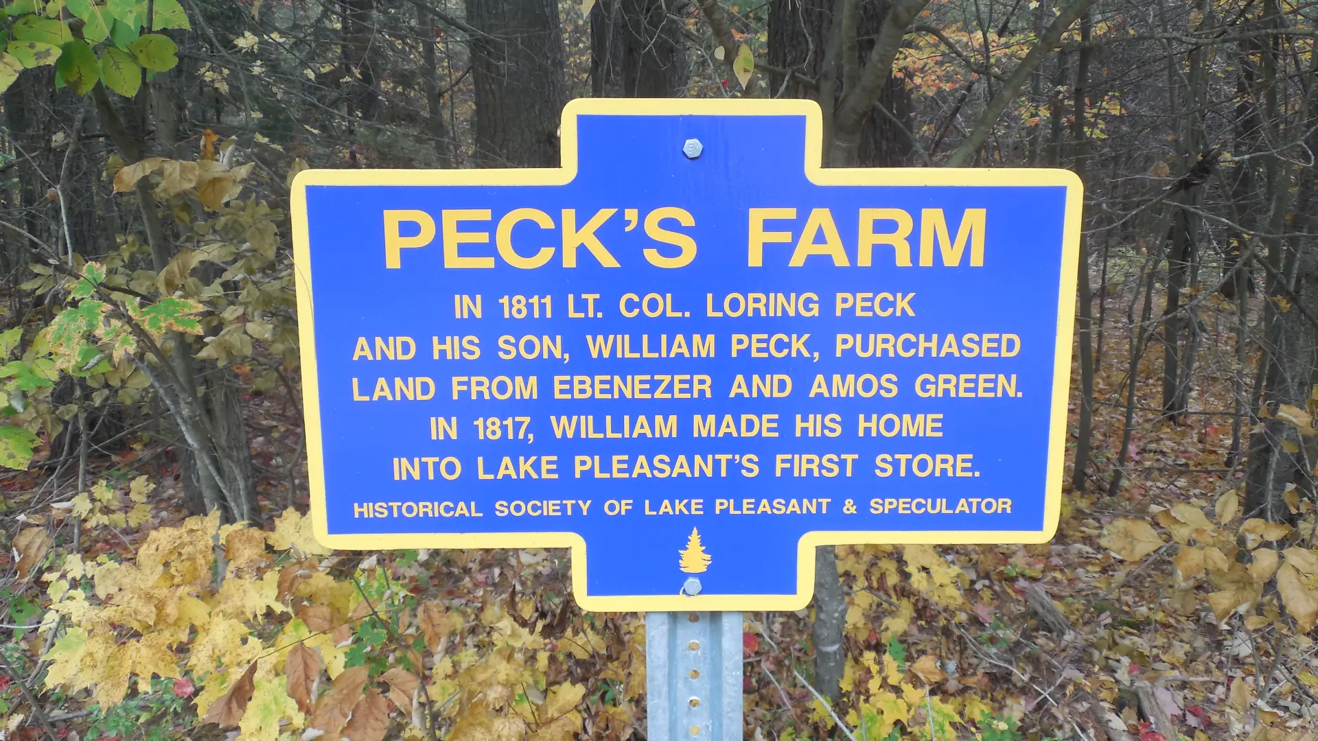 A blue historical sign for Peck's Farm