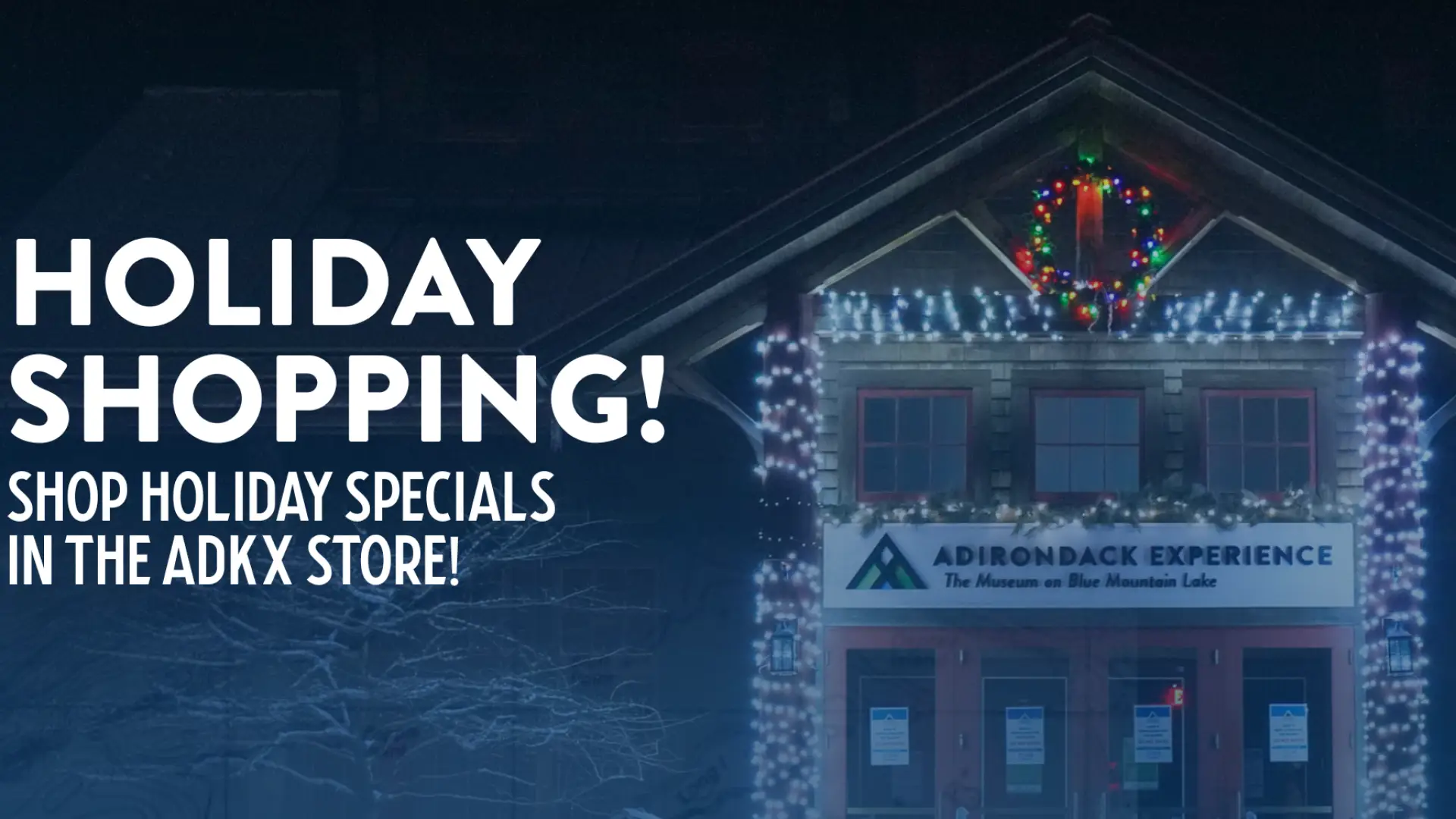 Text reads: Holiday Shopping, Shop Holiday Specials in the ADKX Store!  Image of the Adirondack Experience Visitor Center at night with bright white LED lights and a colorful wreath.
