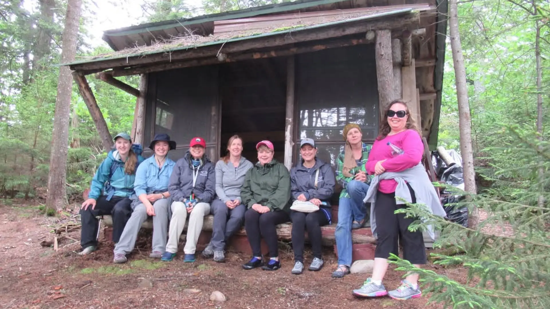 Several ladies sitting in a lean to for a group phot at great camp sagamore