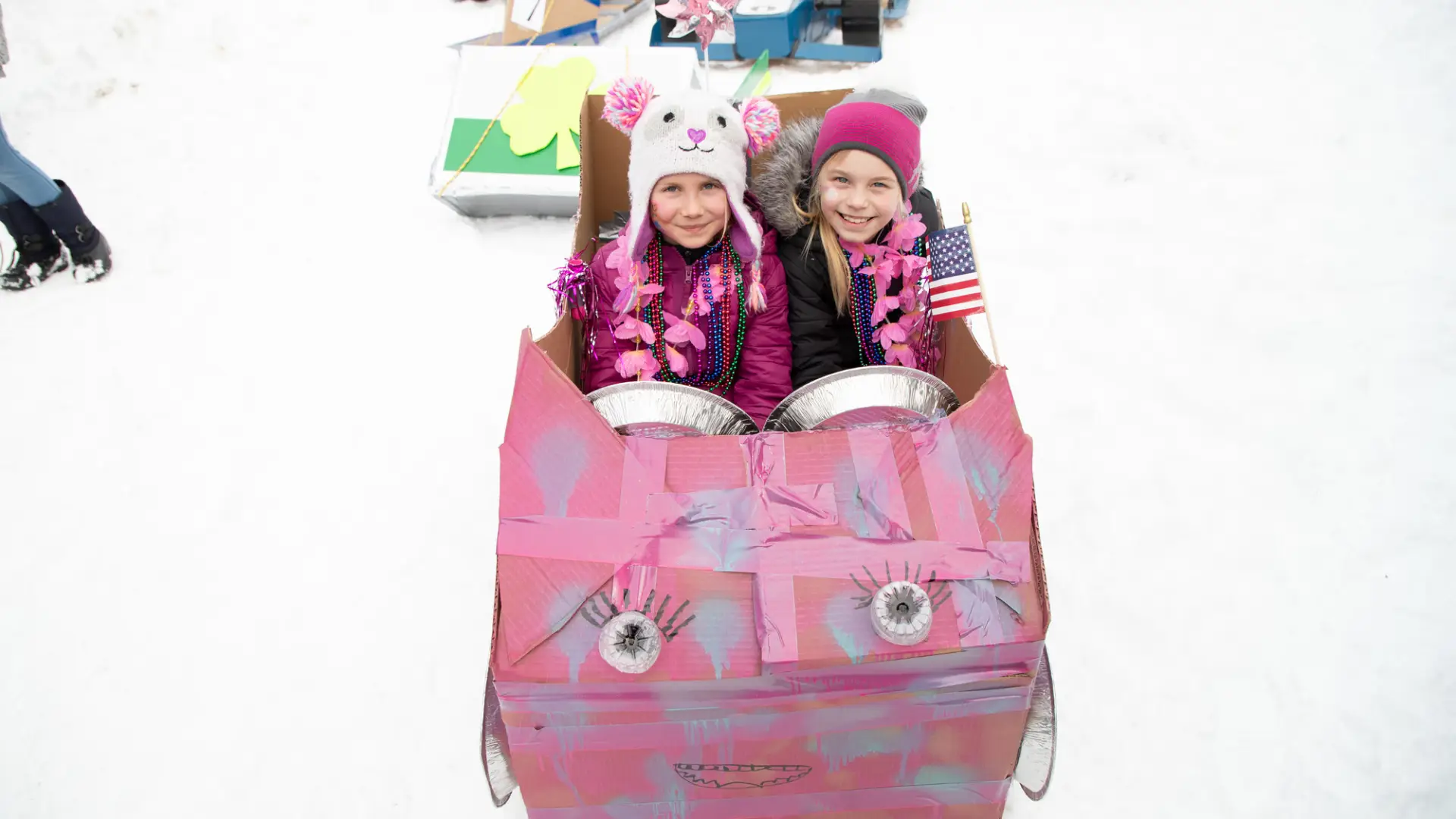 two girls in a pink cardboard sled