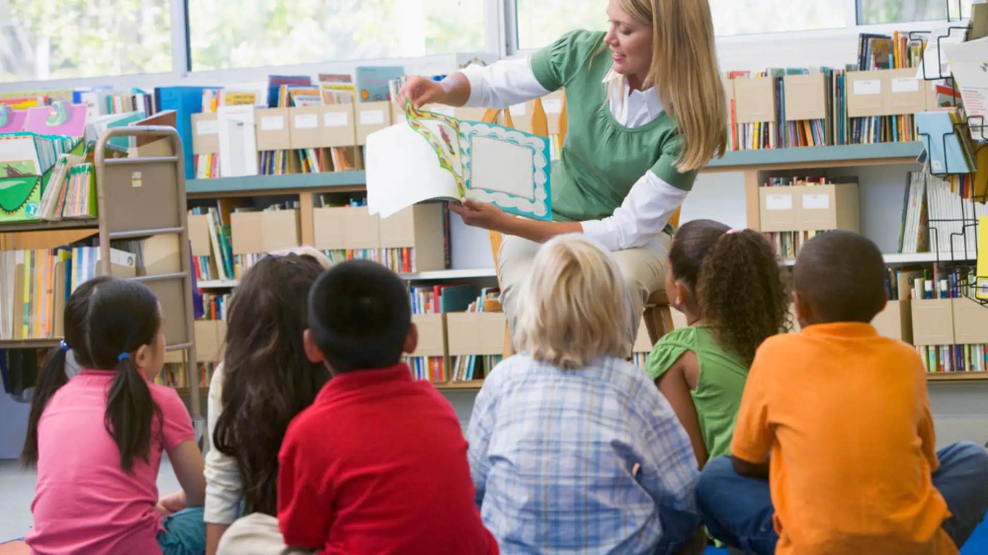 Children sitting on the floor enjoying a story read to them by a woman sitting in a chair