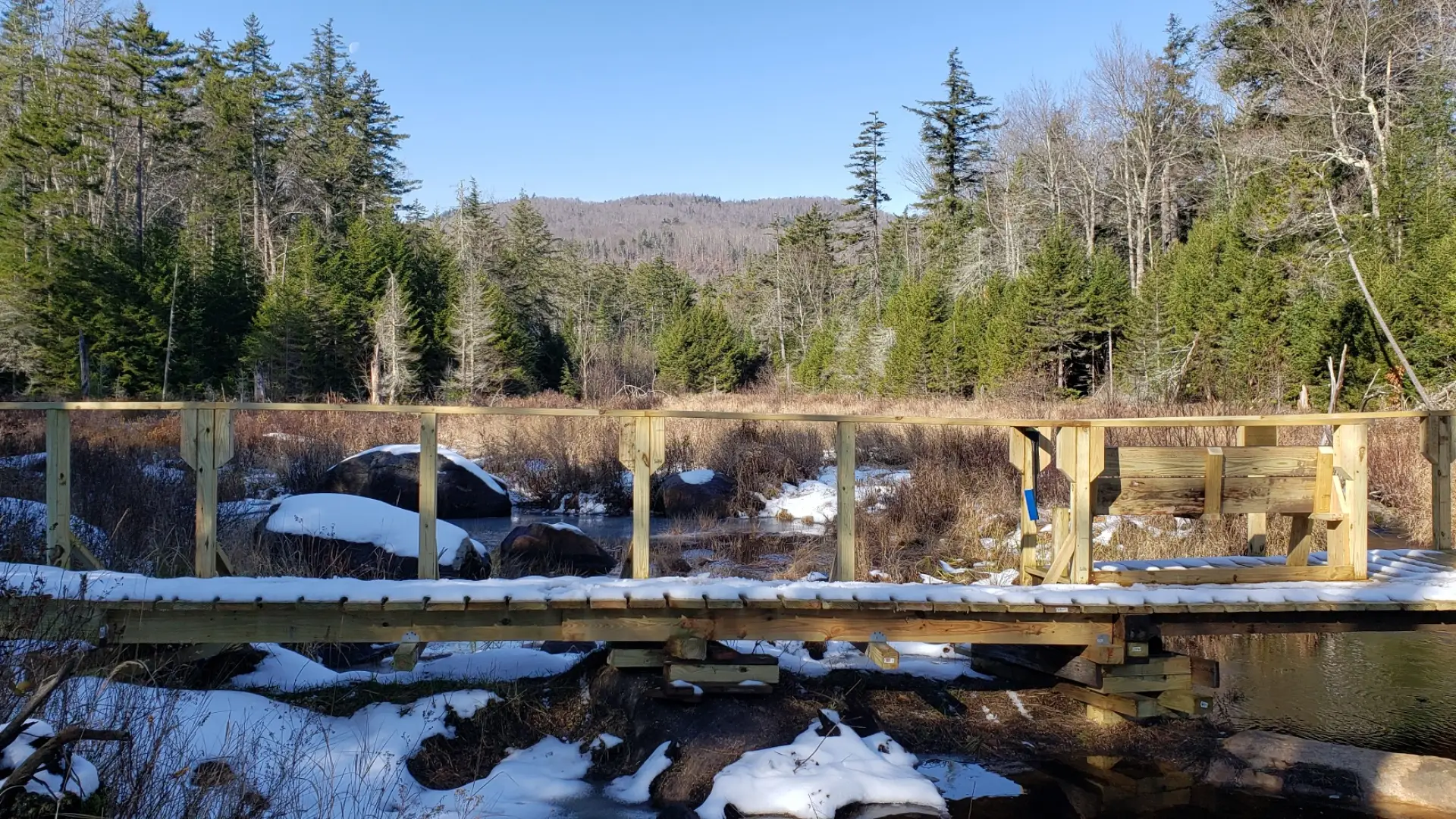 A wooden bridge lightly covered in snow