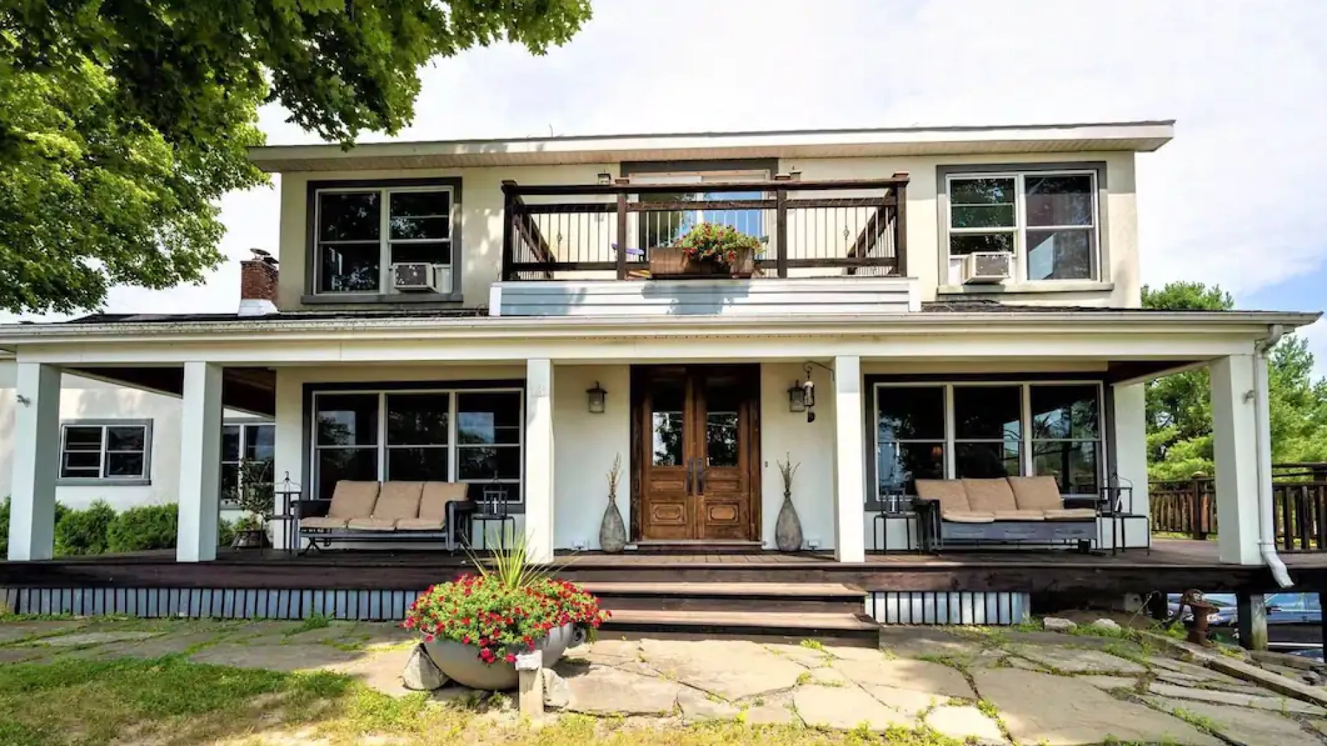 Exterior of The Chateau with grand entry onto wrap-around front porch, elevated balcony and comfortable seating options all around