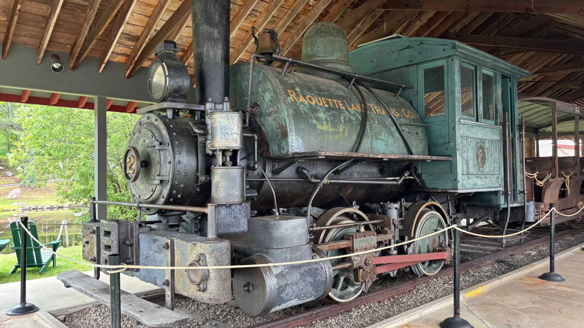 An antique steam engine under a wooden structure