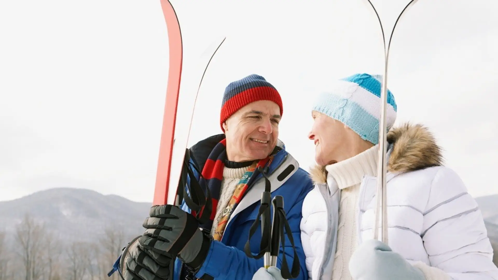 A smiling couple holding snow skis