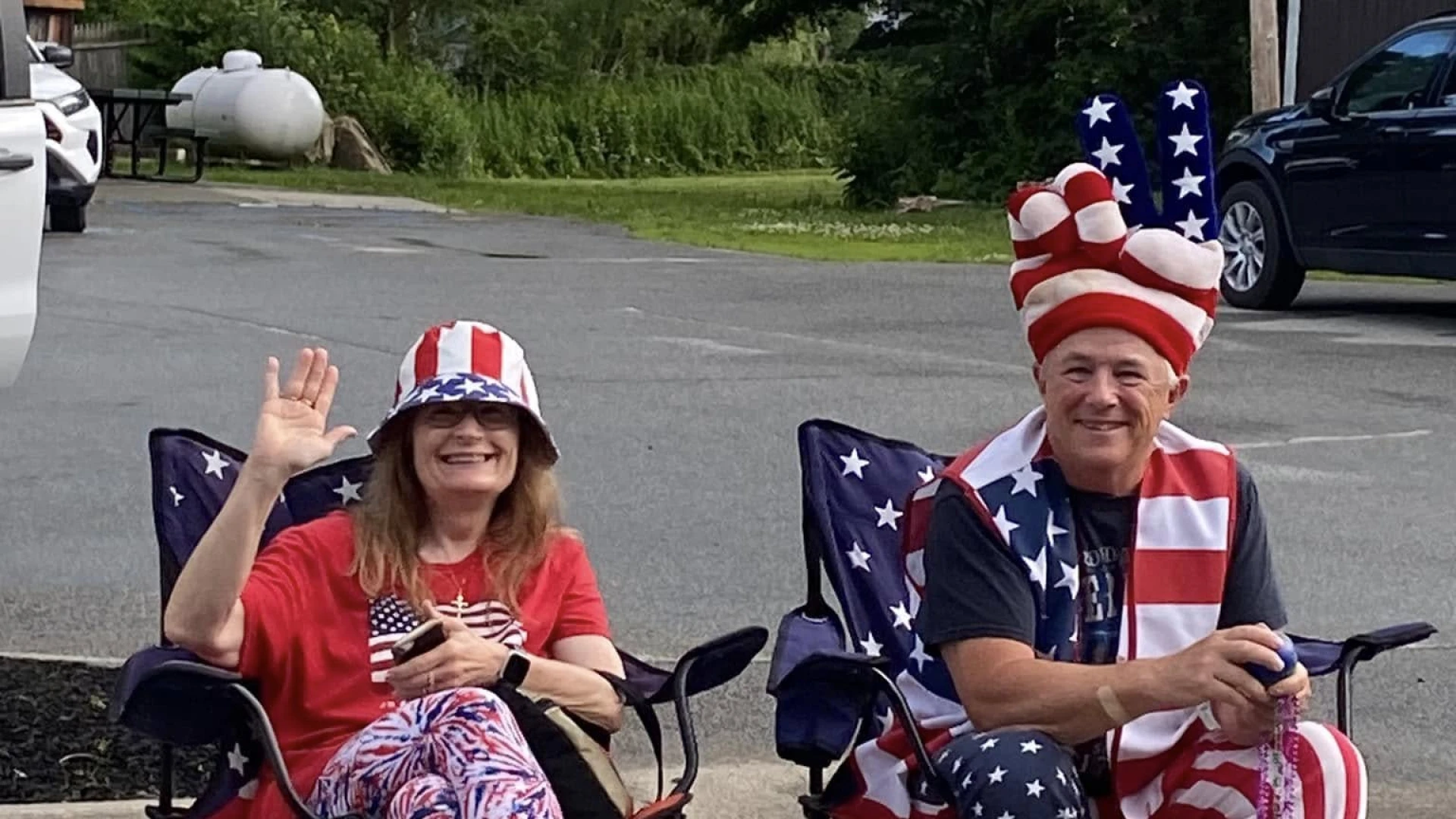 Two people sitting and enjoying the parade dressed in patriotic colors and American Flag clothing