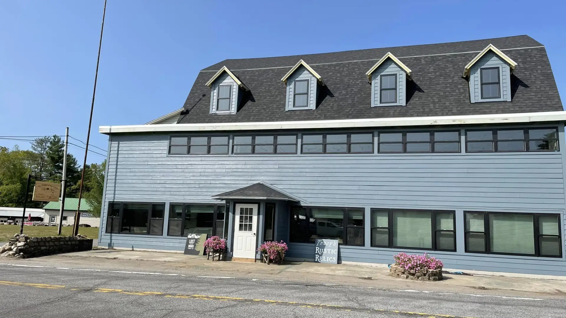 Exterior of a large building with ample parking space an a sign reading Tracy's Rustic Relics