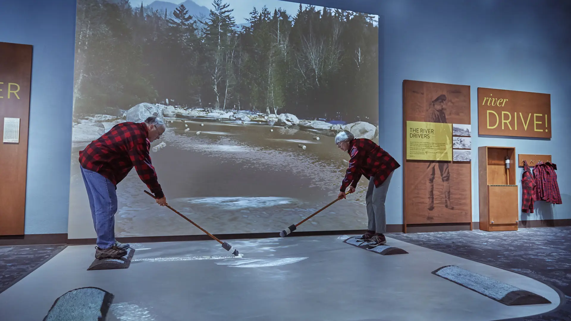 An older man and lady use the river driver log simulator