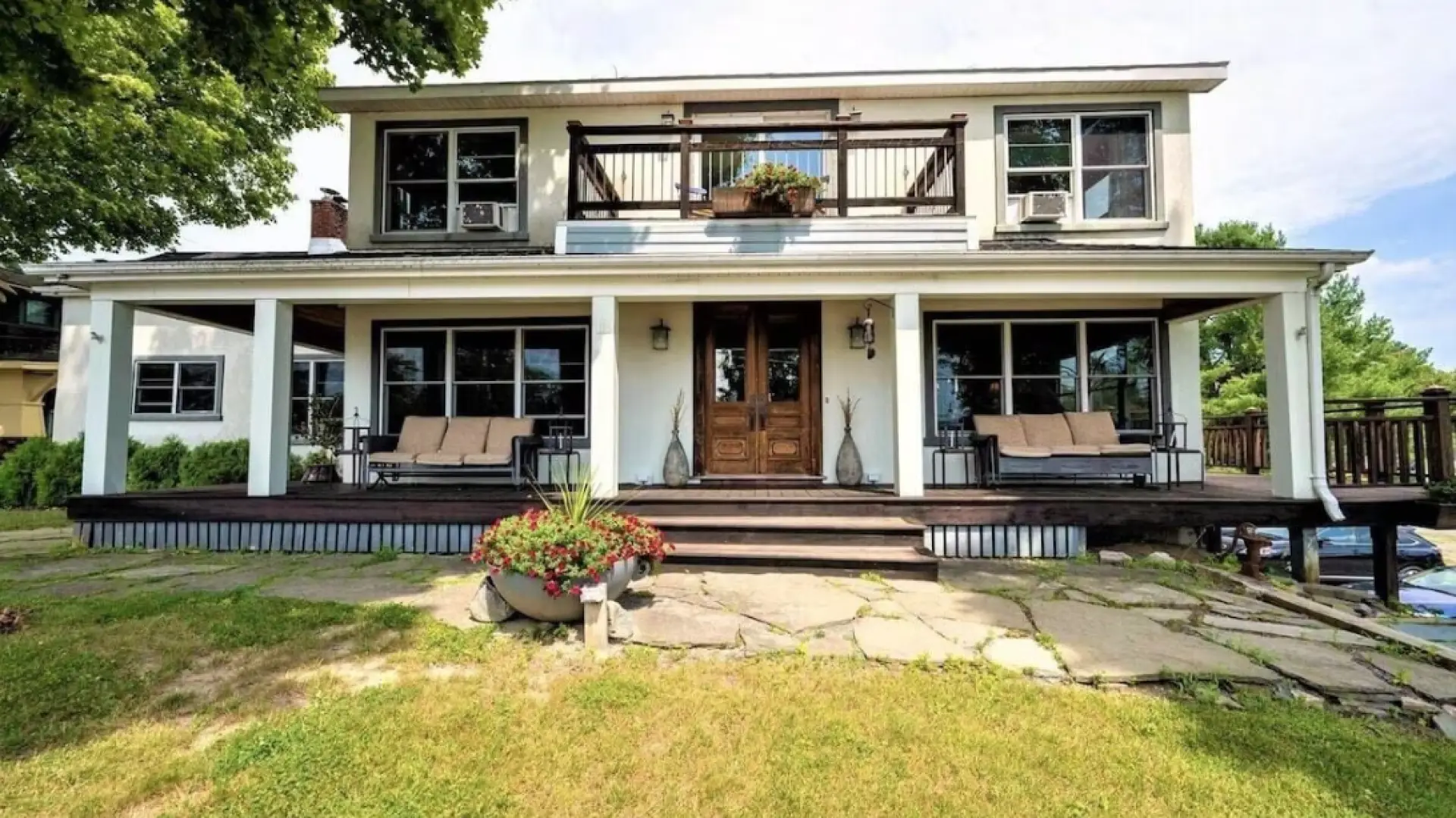 Exterior of The Chateau with grand entry onto wrap-around front porch, balcony and comfortable seating options all around
