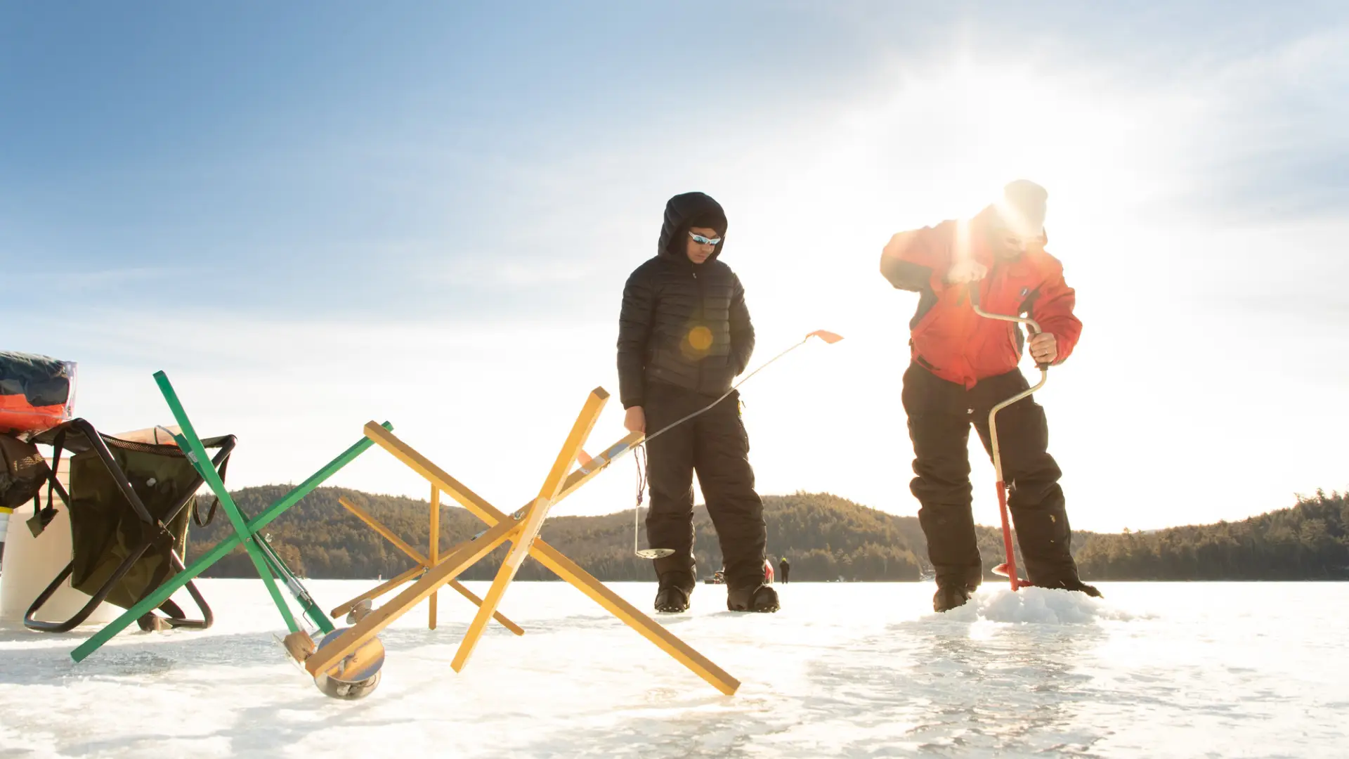 Two ice fishermen setting up gear on a frozen lake. 