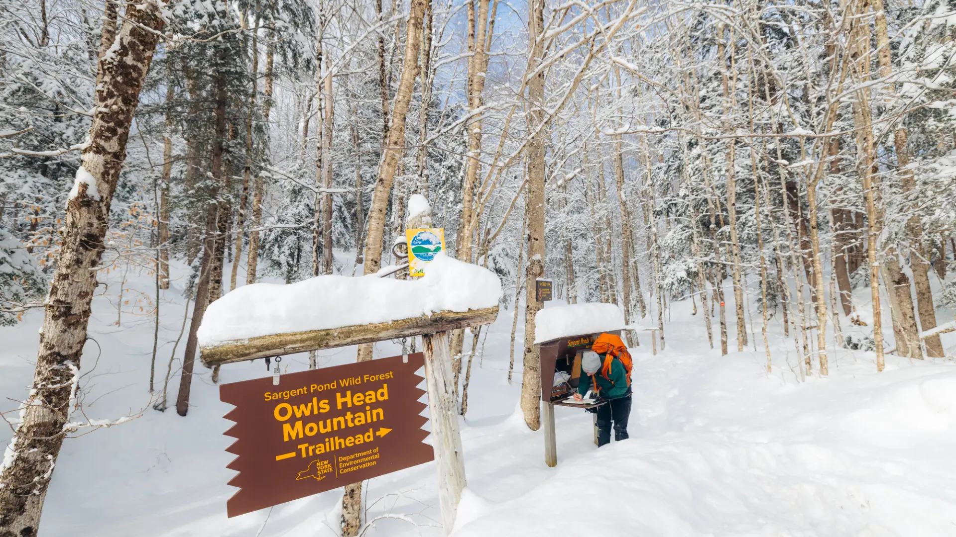 A winter hiker signing into a trail register