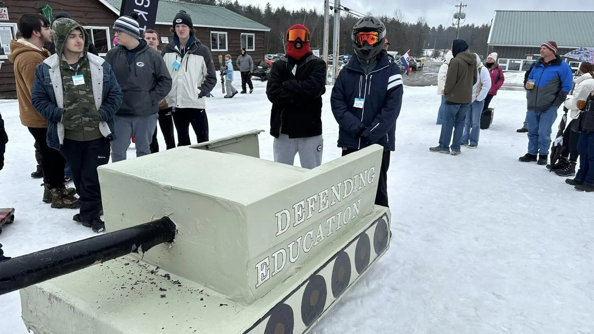 Two sledders standing next to their cardboard sled tank