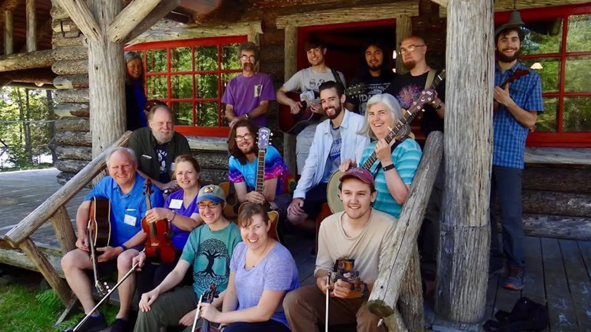 Group of people sitting and standing on the porch at Great Camp Sagamore holdong their instruments