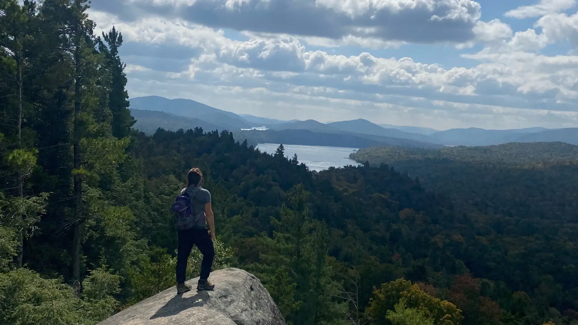 A hiker stands of a rock outcropping of Watch Hill.