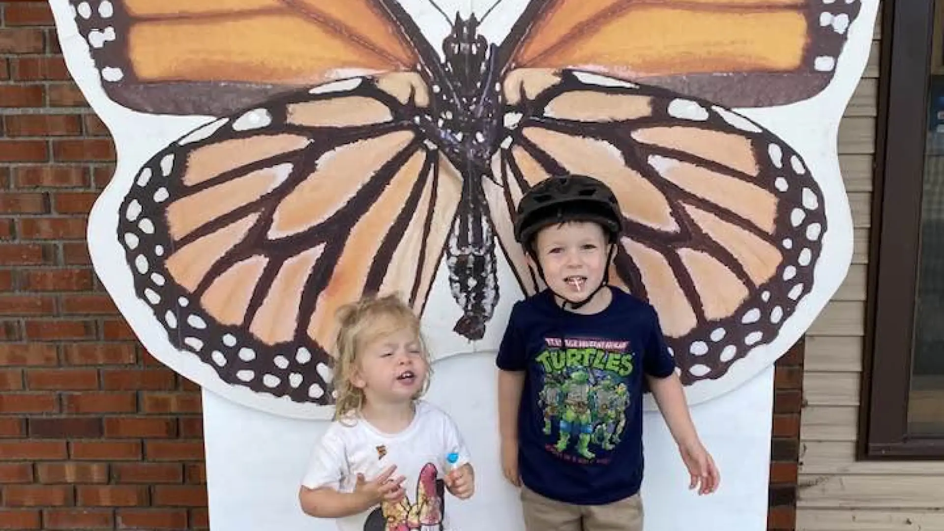 Two children posing in front of the monarch photo prop