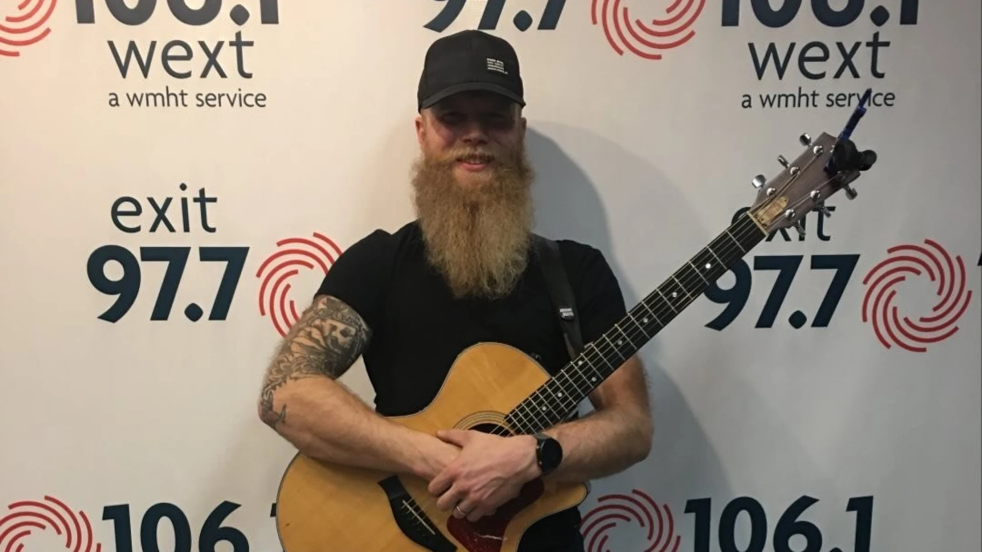 A photo of Josh cleventine holding an acoustic guitar 