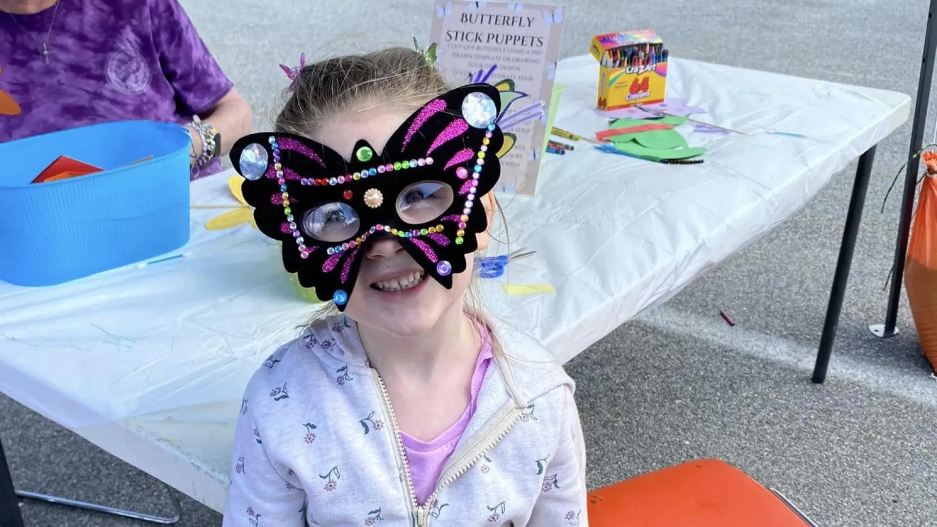 a little girl wearing a butterfly mask that she decorated