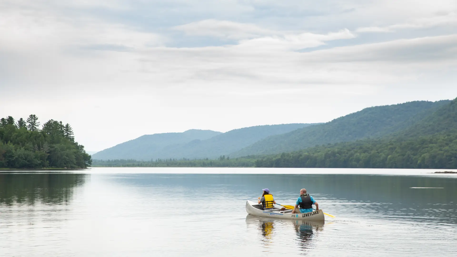 Two people in a canoe paddle across Lewey Lake.