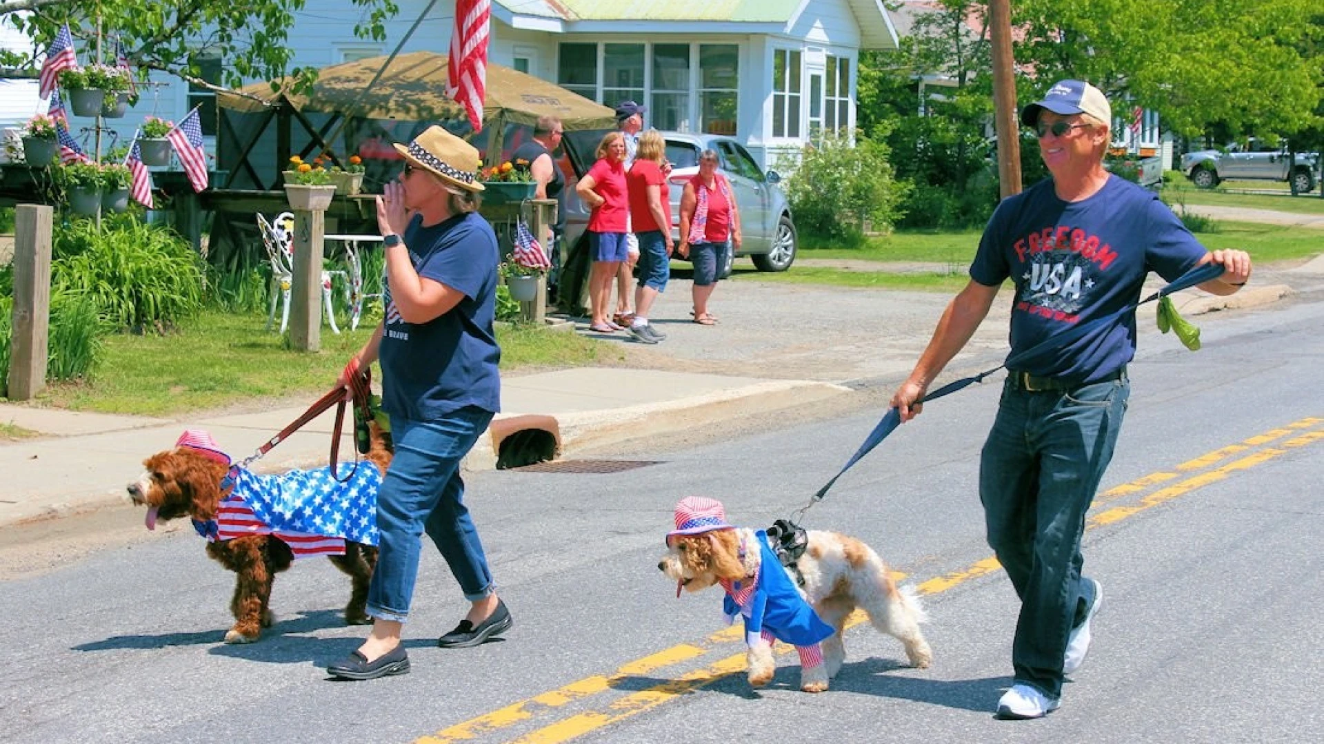 Two men walking marching in the parade with their dogs all dressed patriotically