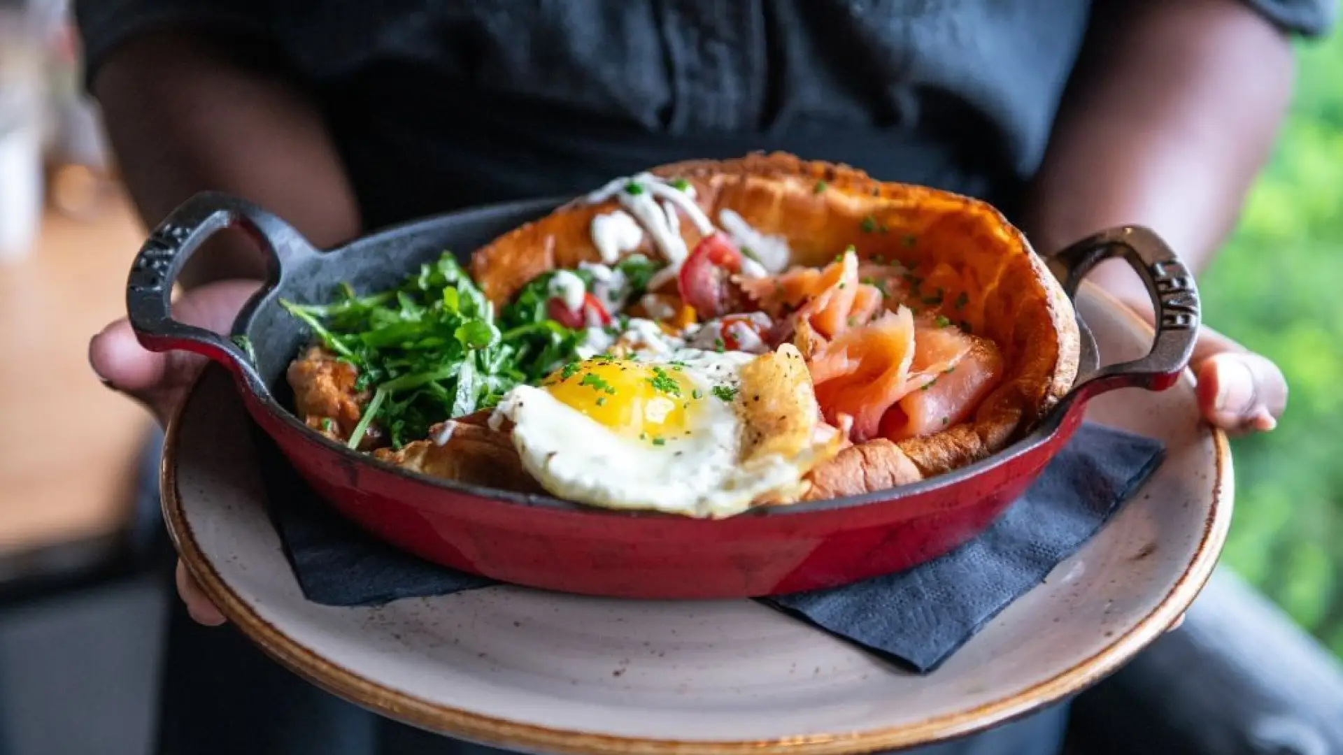 A meal in a wooden bowl with fried egg and greens