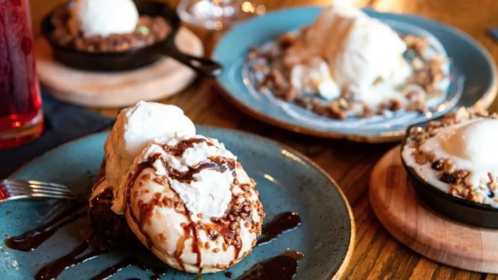 A variety of cakes, cookies, and ice creams drizzled with chocolate.