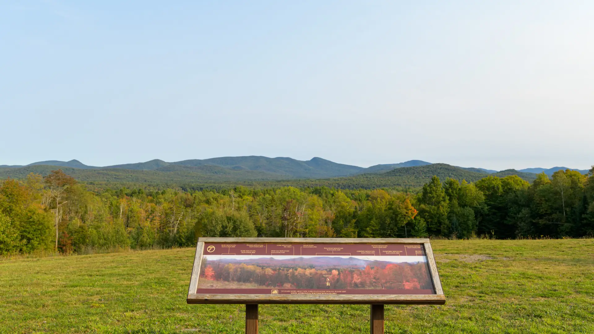 An interpretive sign at a roadside stop overlooking several mountains