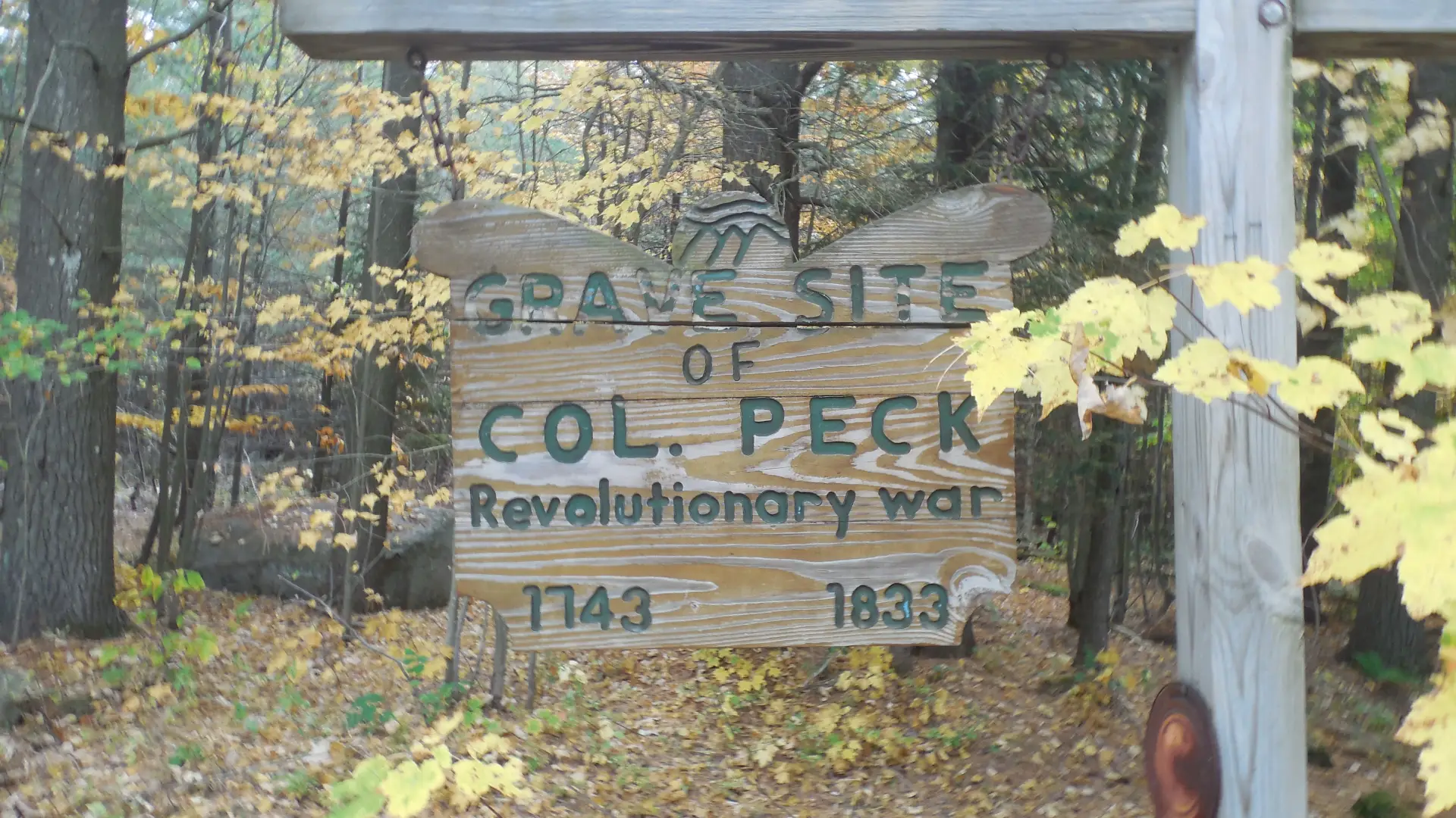 A wooden sign for Col. Peck's grave site