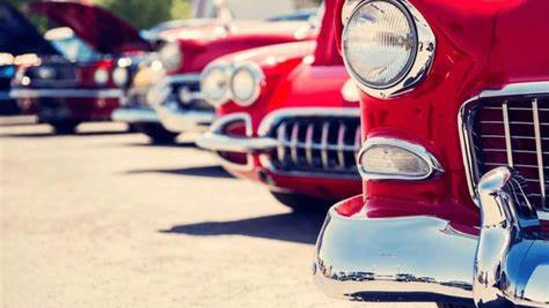 A row of classic red cars parked outdoors.