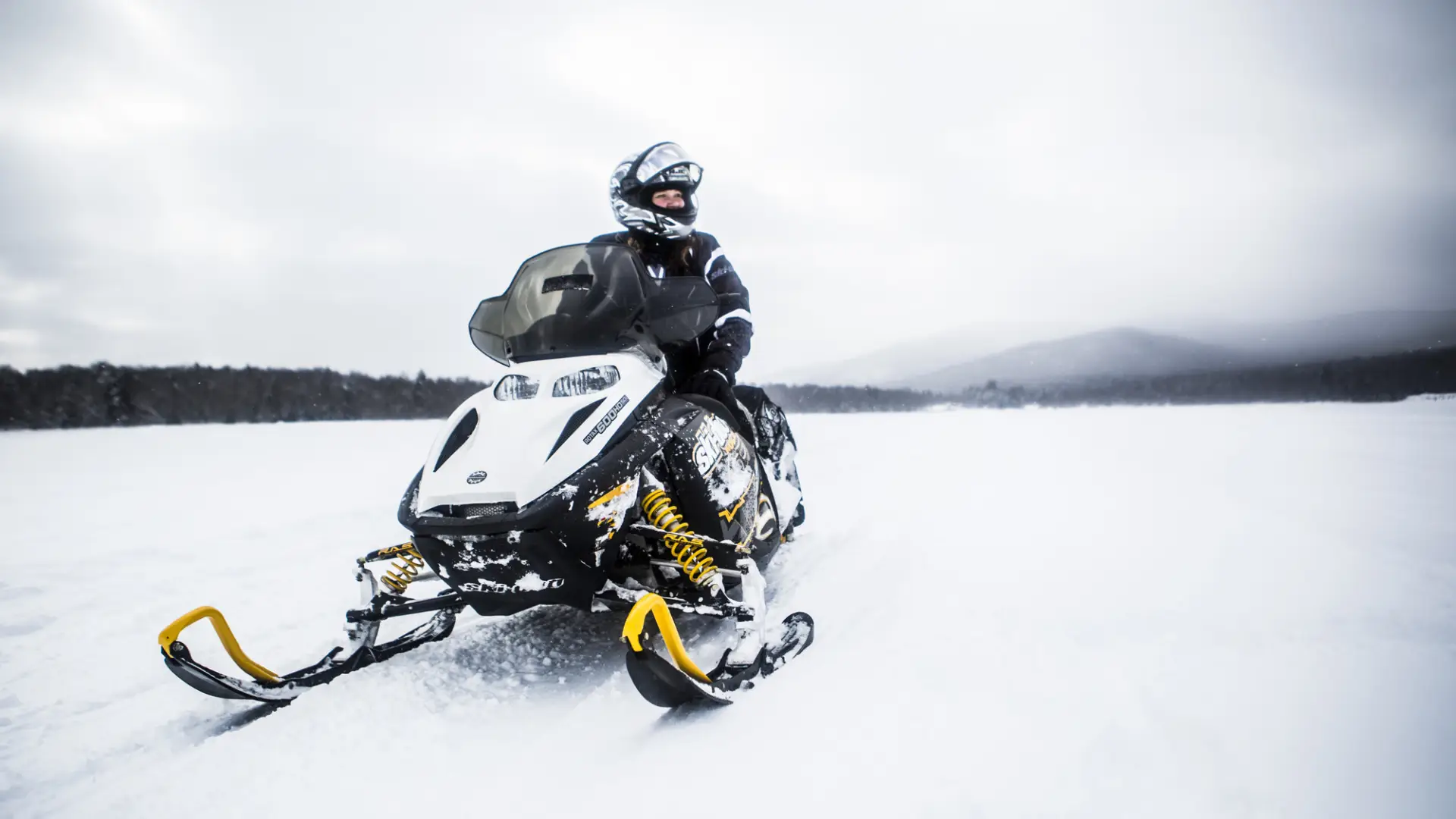 person sitting on a snowmobile on a snow covered frozen lake