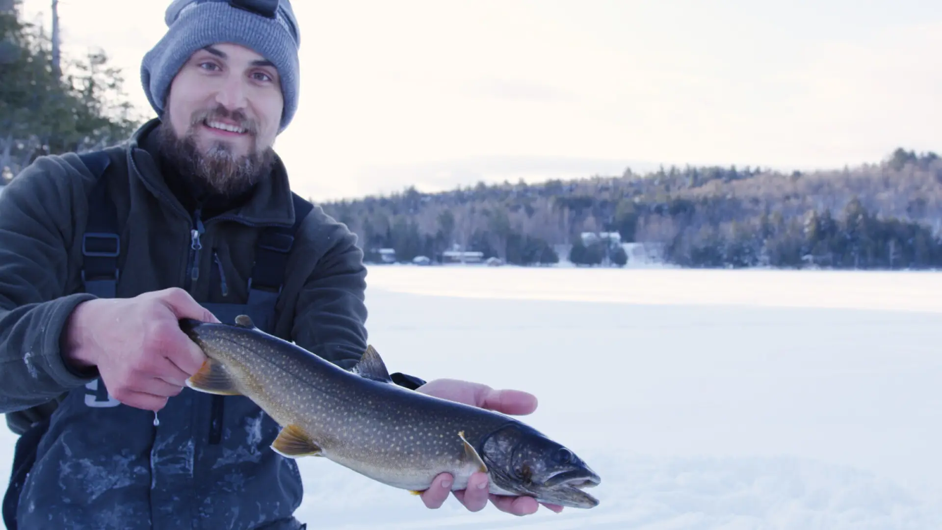 A man holding a fish he caught while ice fishing