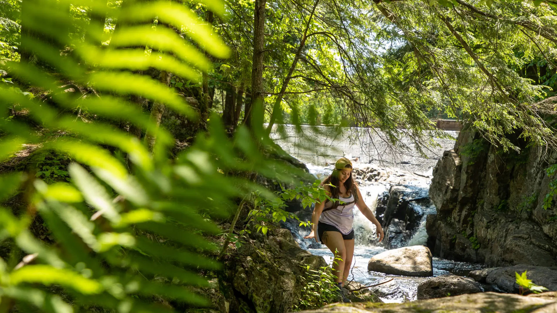 A woman walking in front of a waterfall