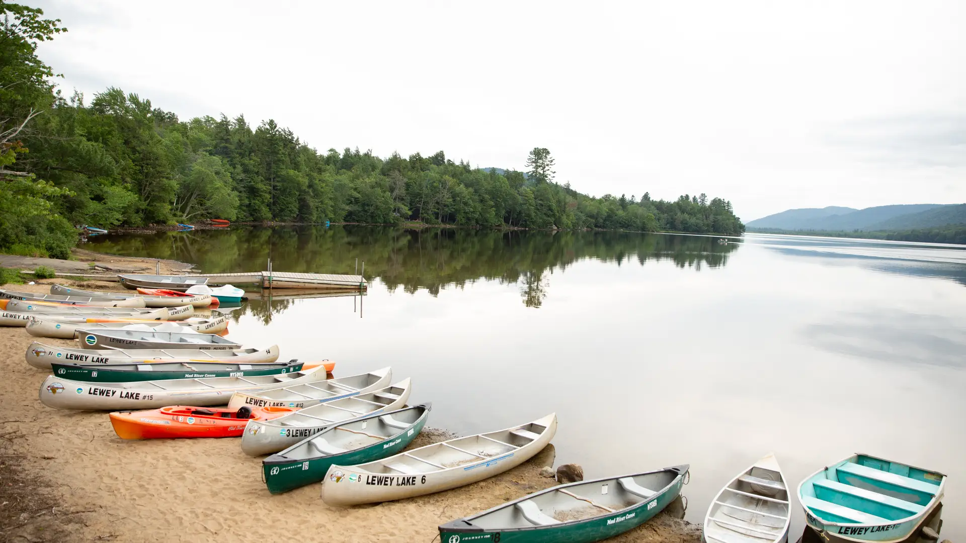 A beach full of rental kayaks and canoes on the shore of a beach at Lewey Lake.