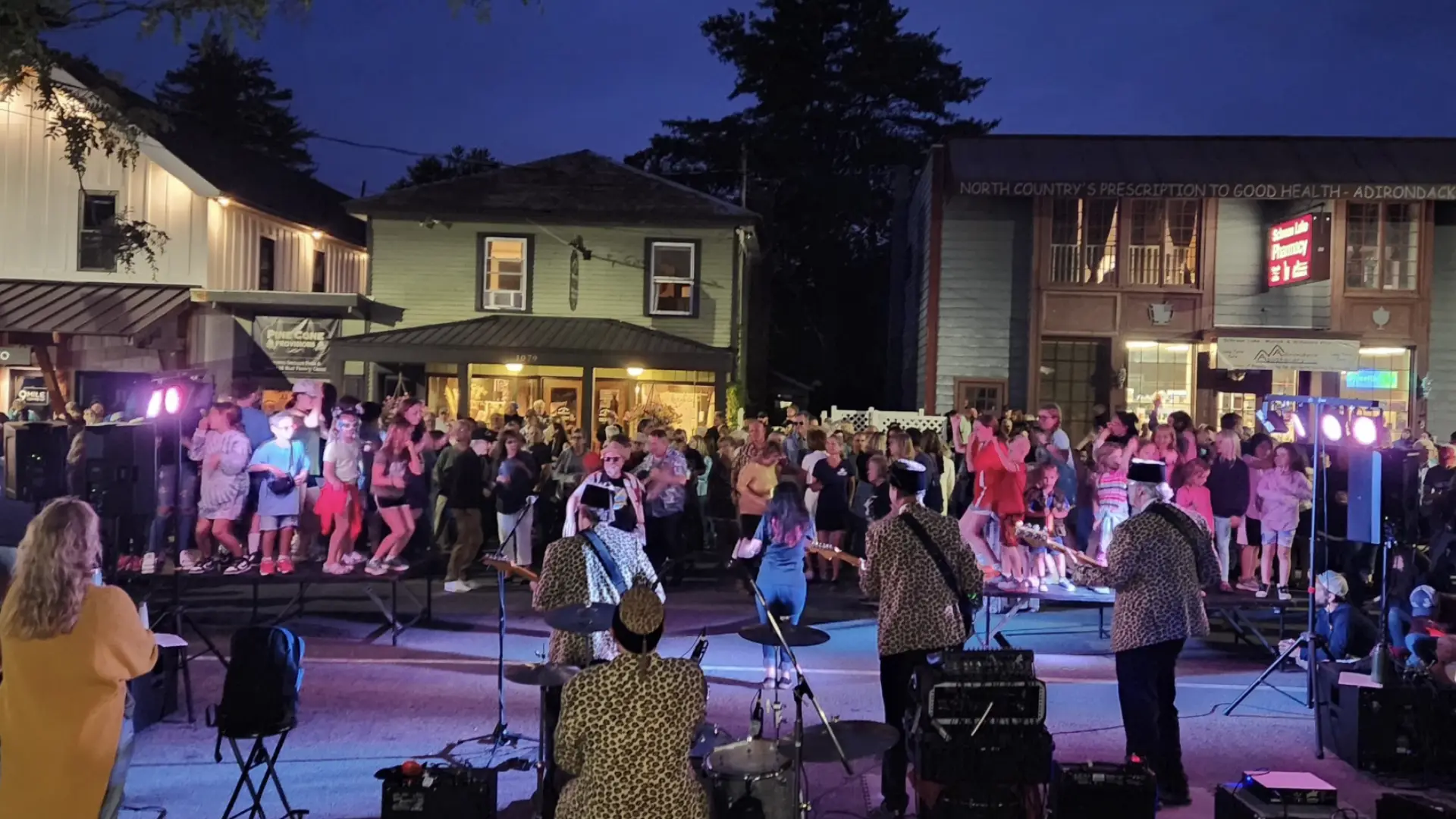 A band plays and people dance in the street in the evening.
