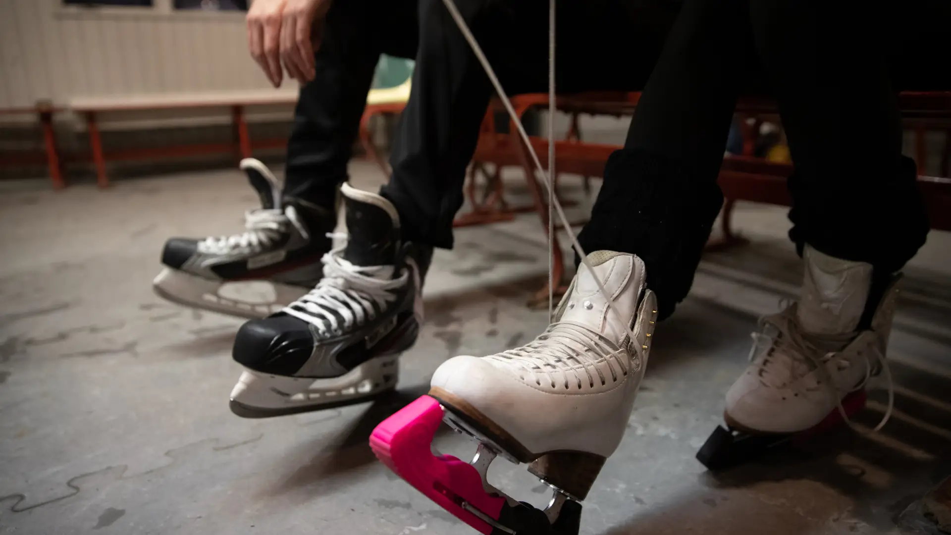 A couple people lacing up their ice skates