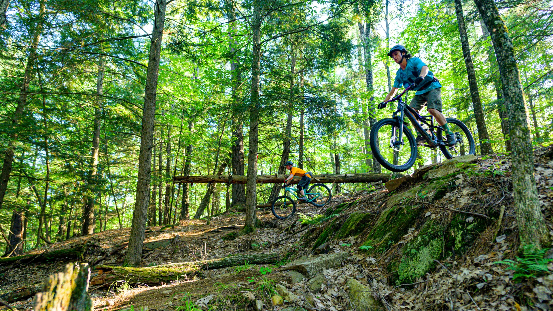A mountain biker rides down a steep rocky section of trail in the woods