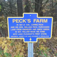 A blue historical sign for Peck's Farm