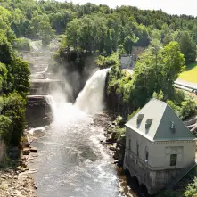 Water crashes over the falls with a building near by.