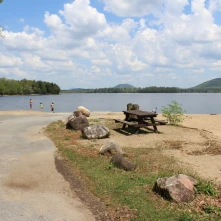 A beach with a boat ramp, picnic table, and mountain views