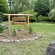 Rustic Footbridge Park sign with lawn and trees in the background
