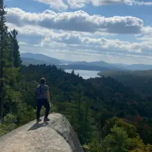 A hiker stands of a rock outcropping of Watch Hill.